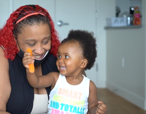 A woman and a child the child is holding an orange item.