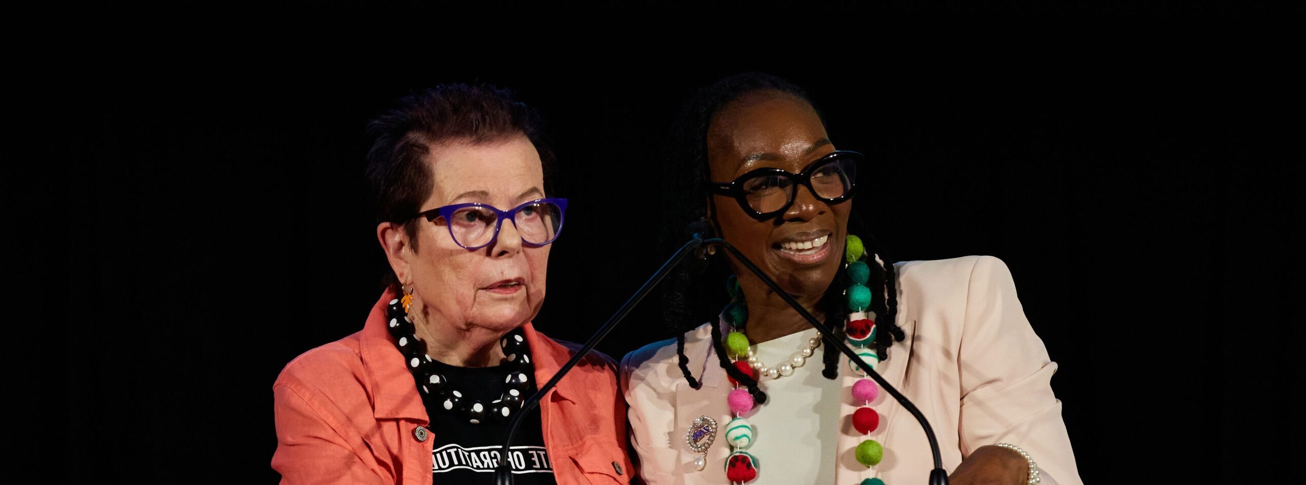 two women at a podium gazing at audience