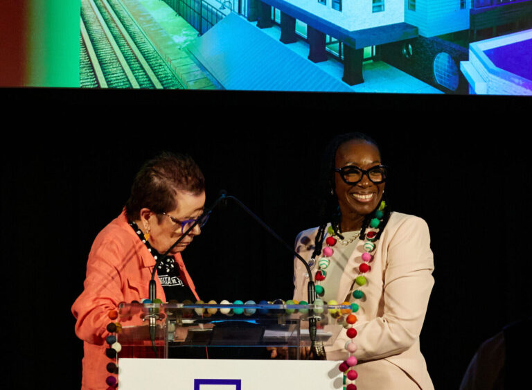 a smiling woman gazes over a podium.