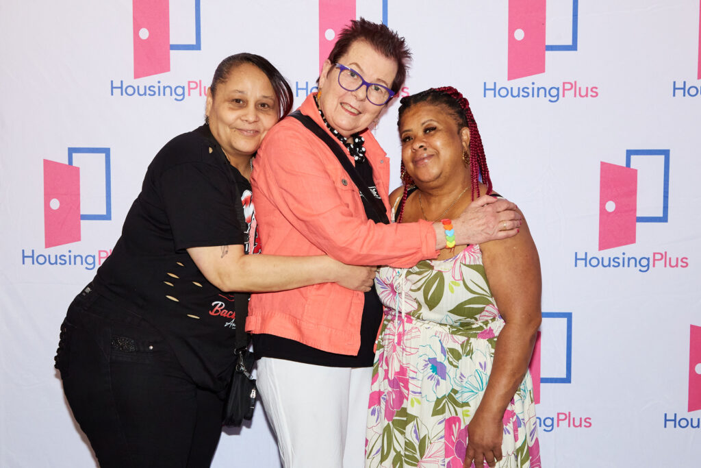 Three women in a fun pose in front of a step and repeat