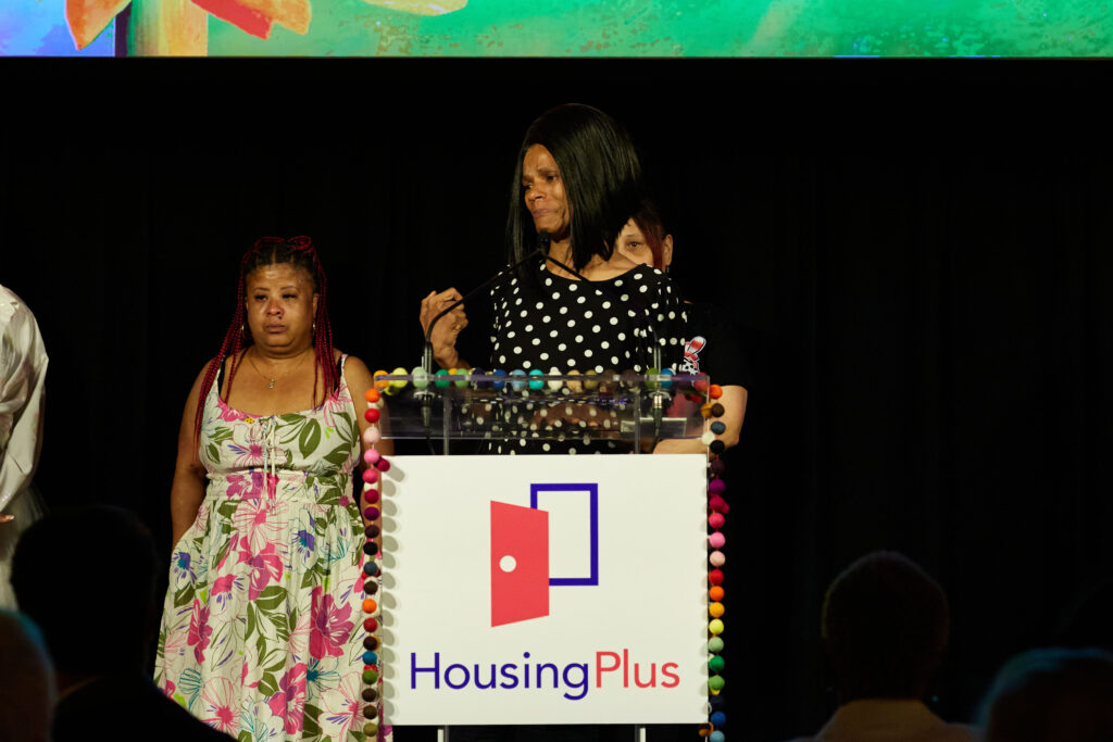 A woman in a polka dotted dress stands at podium
