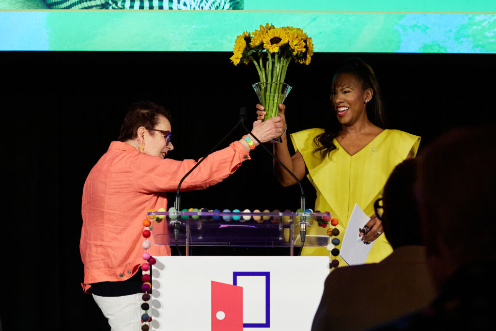 A pair of women hold up a bouquet of sunflowers