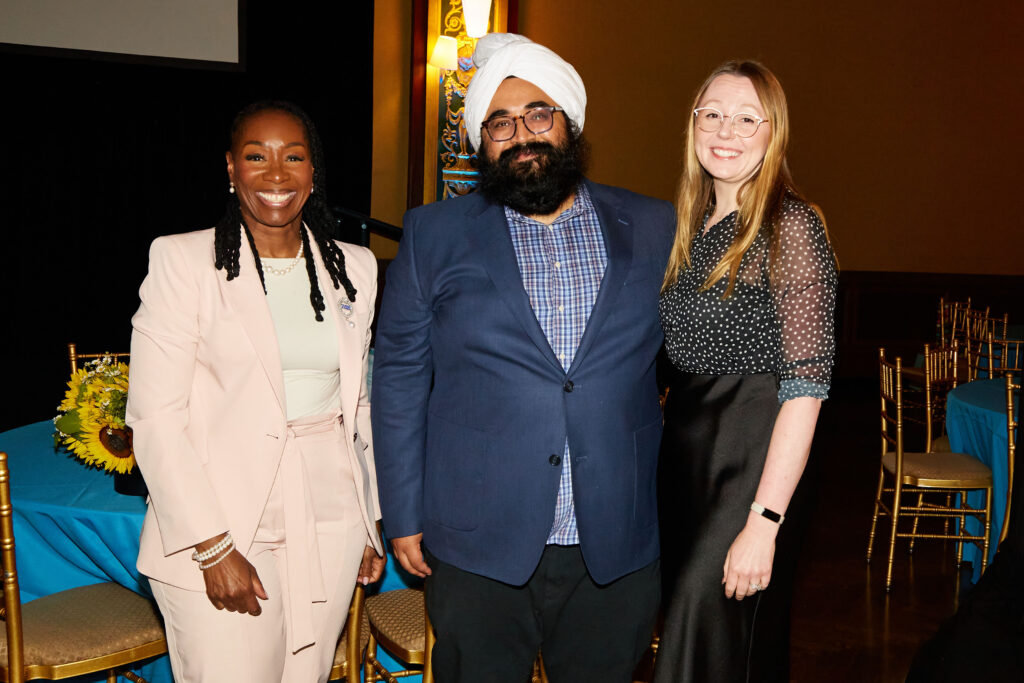 Two women stand on either side of a man with a beard