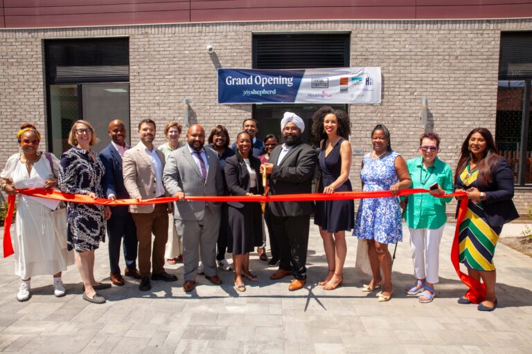 A large group cuts the ribbon at Shepherd Avenue supportive housing building