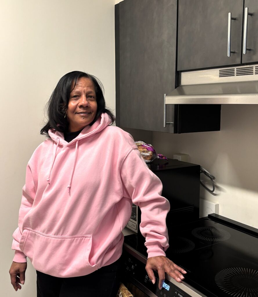 HousingPlus tenant Debra stands in the kitchen of her studio apartment in East New York.